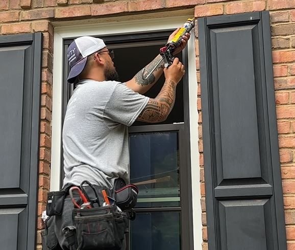 Worker sealing window perimeter on a brick wall using a caulking tool